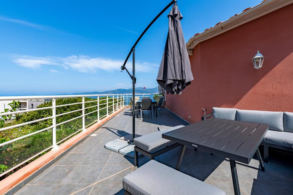 un patio avec une table et un parasol dans l'établissement Canelli - Magnifique Vue Mer, à Pietrosella