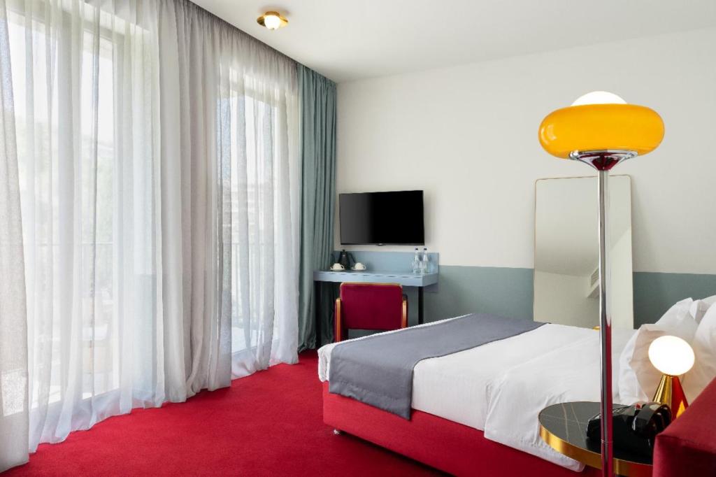 a hotel room with a bed with a red carpet at Stars by Castor & Pollux in Tbilisi City