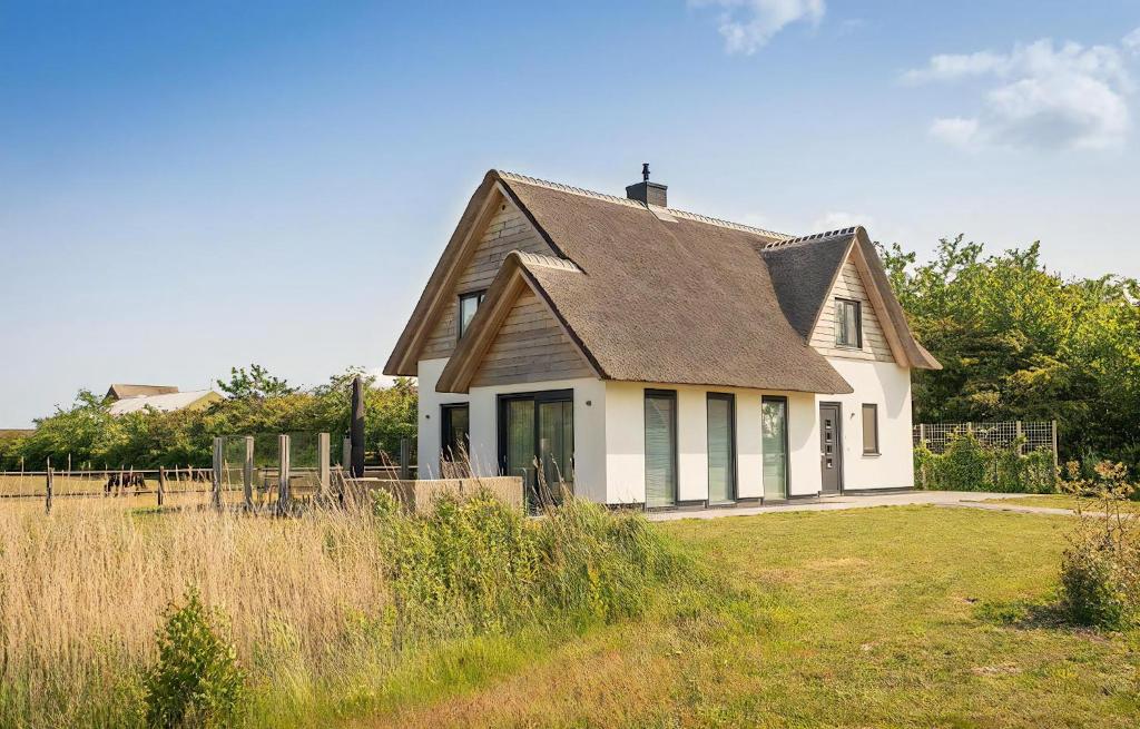 a white house with a brown roof in a field at Z Luxe Villa Bouwlust in De Cocksdorp