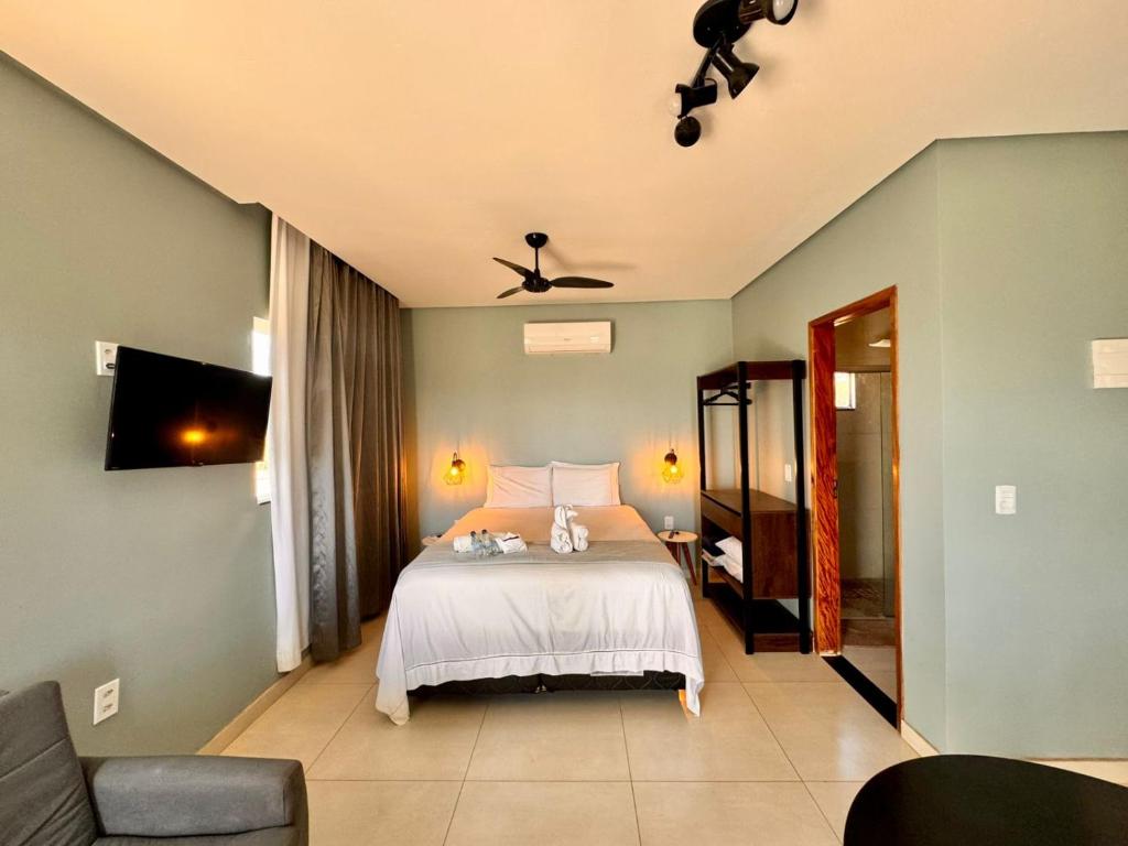 a bedroom with a bed and a couch and a tv at Flat Jade - Alto Paraíso - Chapada dos Veadeiros in Alto Paraíso de Goiás