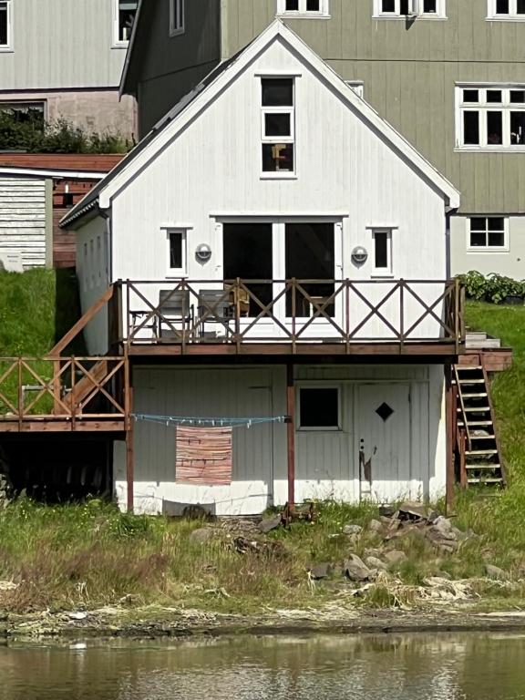 une maison blanche avec un balcon au-dessus dans l'établissement Cottage by the waterfront, à Vestmanna