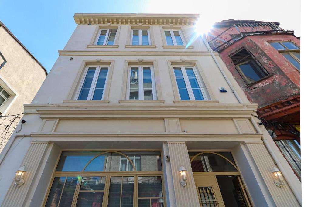 Un grand bâtiment blanc avec le soleil brillant sur lui dans l'établissement Balatella Suites, à Istanbul