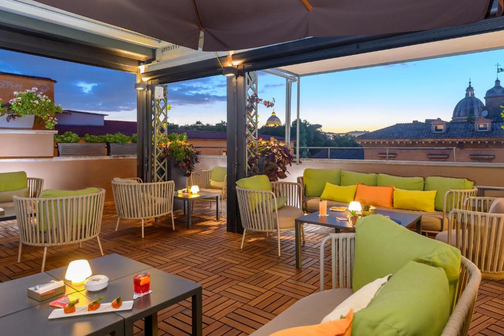 a patio with couches and tables on a balcony at Hotel Indigo Rome - St. George by IHG in Rome