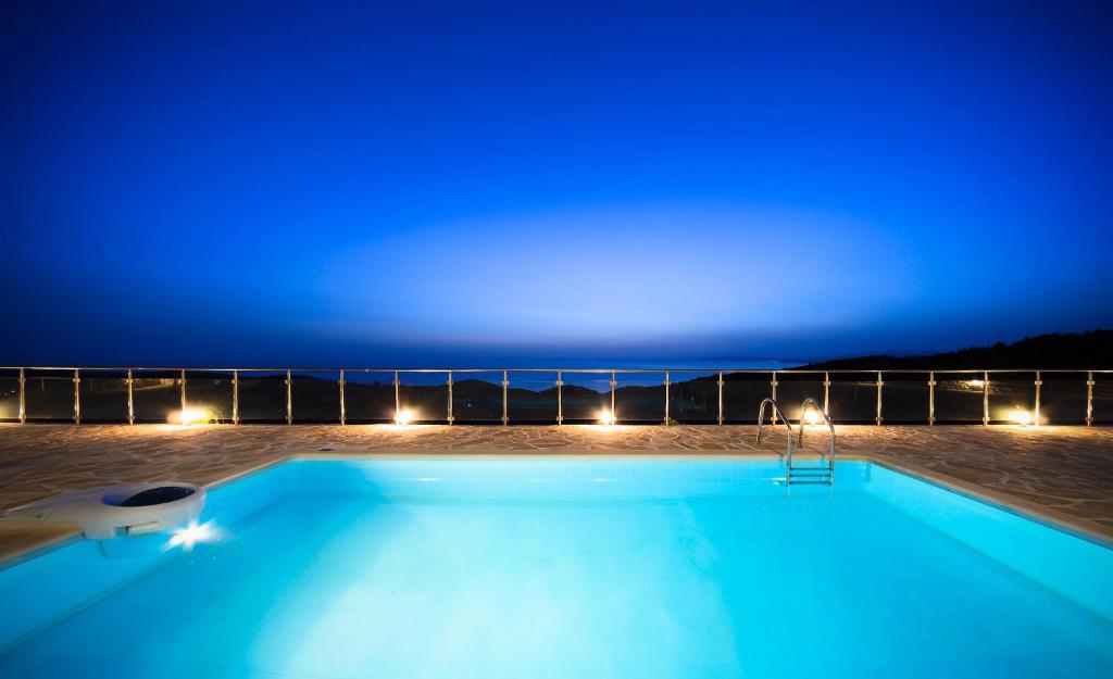 una piscina notturna con luci blu di Orient Villas Volimes a Volímai