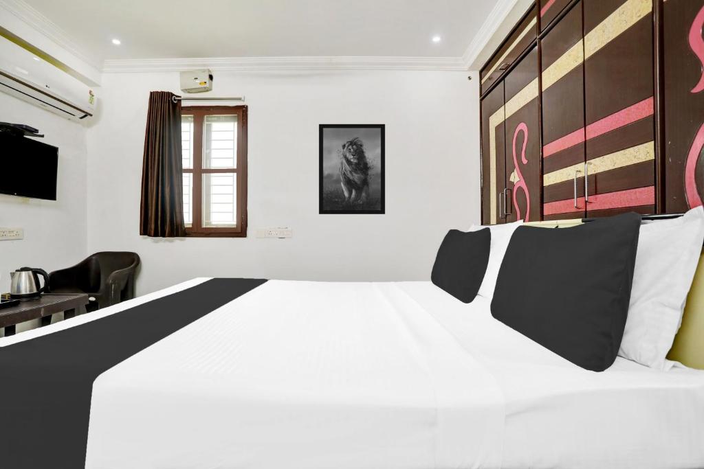 a bedroom with a large white bed with black and white pillows at Super Hotel O J3 LUXURY ROOMS in Guntūr