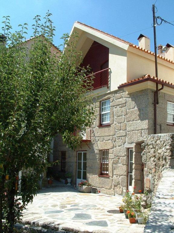 a large stone house with a tree in front of it at casa do meio da vila suites in Loriga