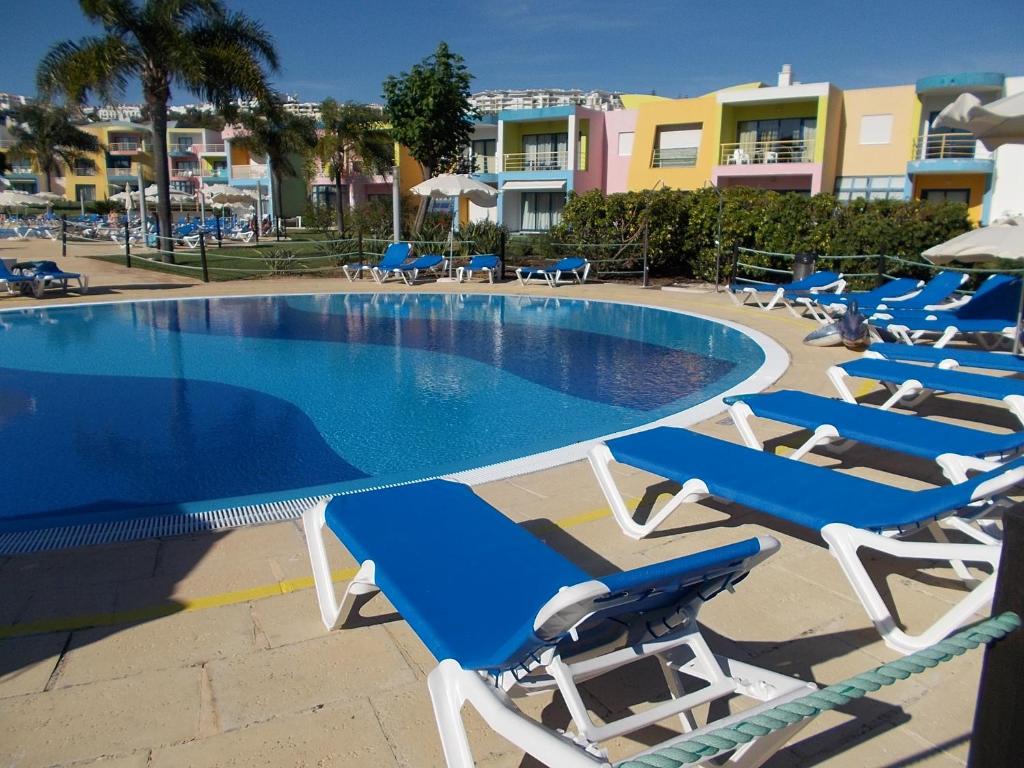 a group of lounge chairs and a swimming pool at T1 e T2 Marina Albufeira apartments in Albufeira