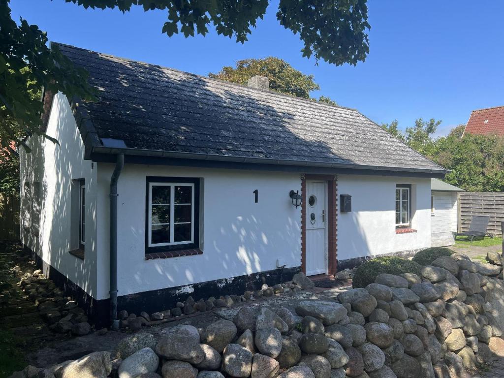 a small white cottage with a stone wall at Ferienhaus-„Alte-Schmiede“ in Westerland (Sylt)