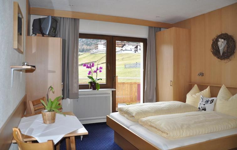 Schlafzimmer mit einem Bett, einem Tisch und einem Fenster in der Unterkunft Haus Leo in Sölden