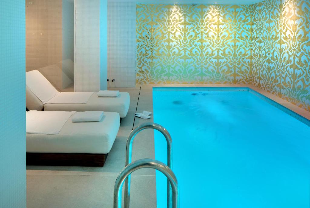 a living room with a swimming pool and a couch at Hôtel Kleber Paris & Spa in Paris