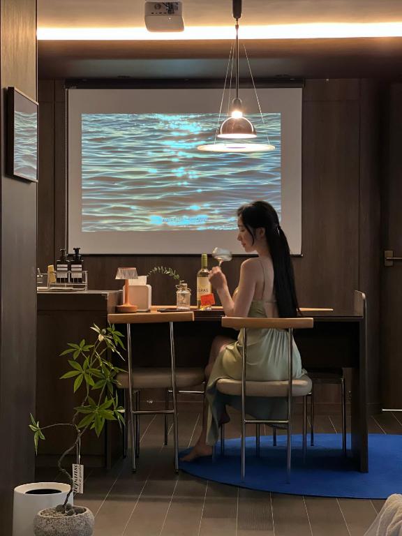 a woman sitting at a table in front of a screen at BUSAN Stay 404 in Busan
