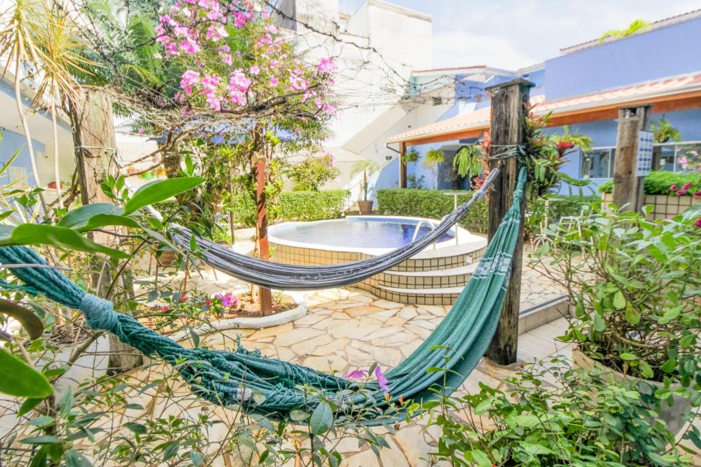 a hammock in front of a house with a pool at Velinn Pousada Remanso do Mar in Ubatuba