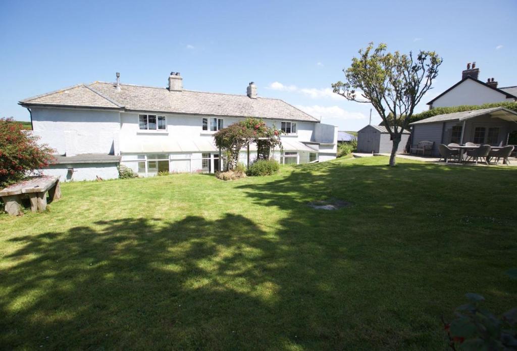 a large white house with a large grass yard at Penrose Cottage in Bude