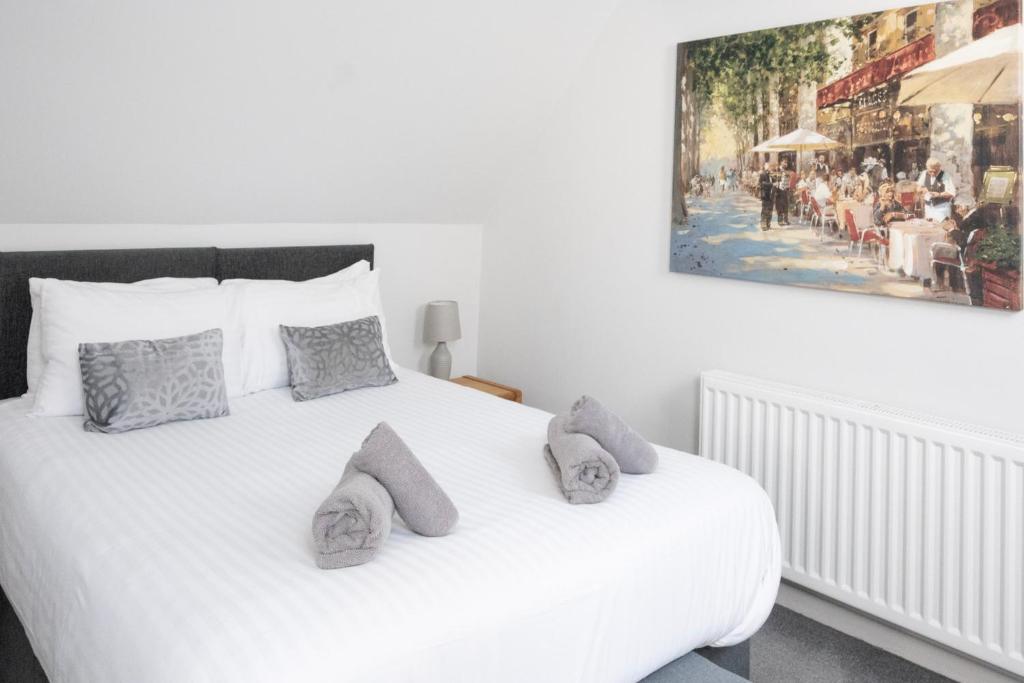 a white bed with pillows and a painting on the wall at Hedgehog Cottage in Bury Saint Edmunds