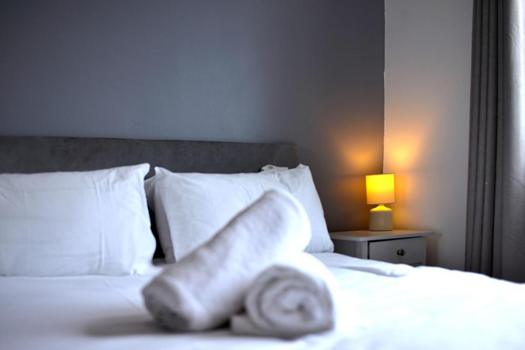 a persons leg laying on a bed with pillows at Broad Gauge Apartments in Wolverhampton