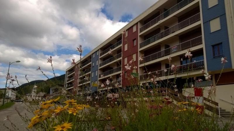 a building with a bunch of flowers in front of it at Appartement spacieux tout confort pied des pistes in Lélex