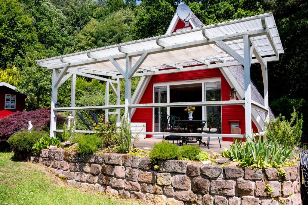 a red cottage with a stone retaining wall at Roter Fuchsbau am Eichwald in Gossersweiler-Stein