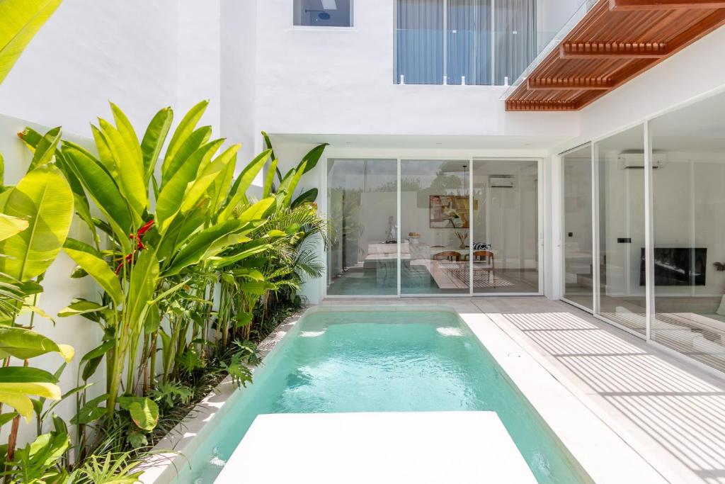 een binnenzwembad in een huis met planten bij White Palm Villa in Canggu