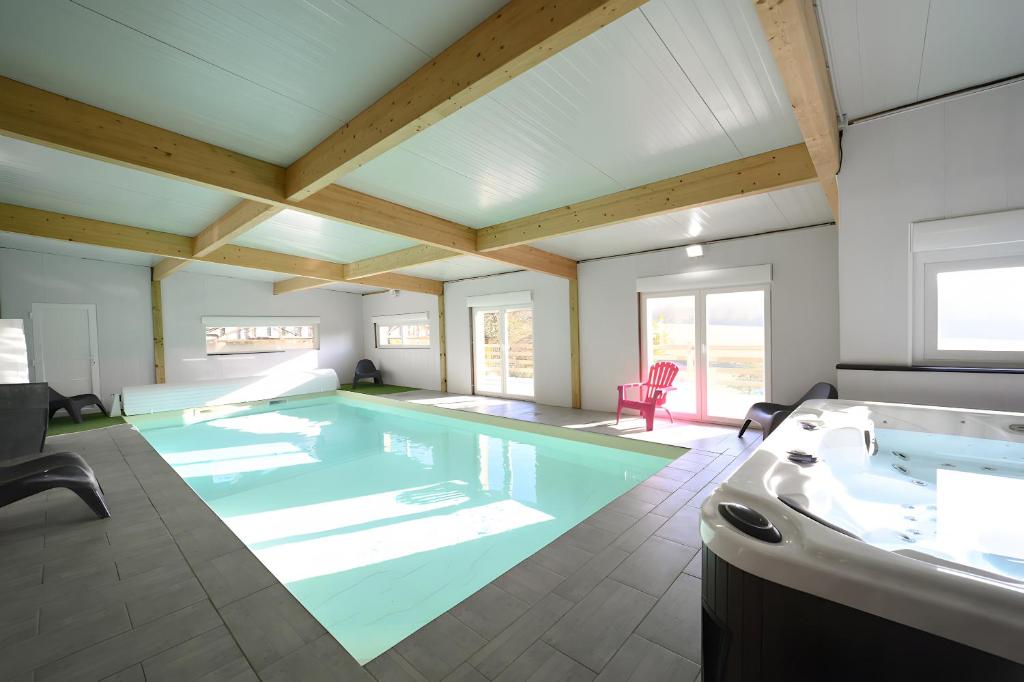 a large swimming pool in a room with a tub at A l oree du bois in Signy-lʼAbbaye