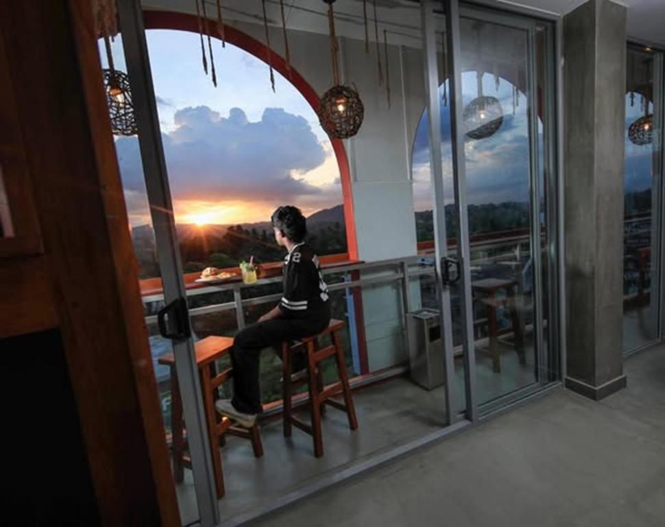 a man sitting in a chair on a balcony with a view at The Selene city hotel in Kandy