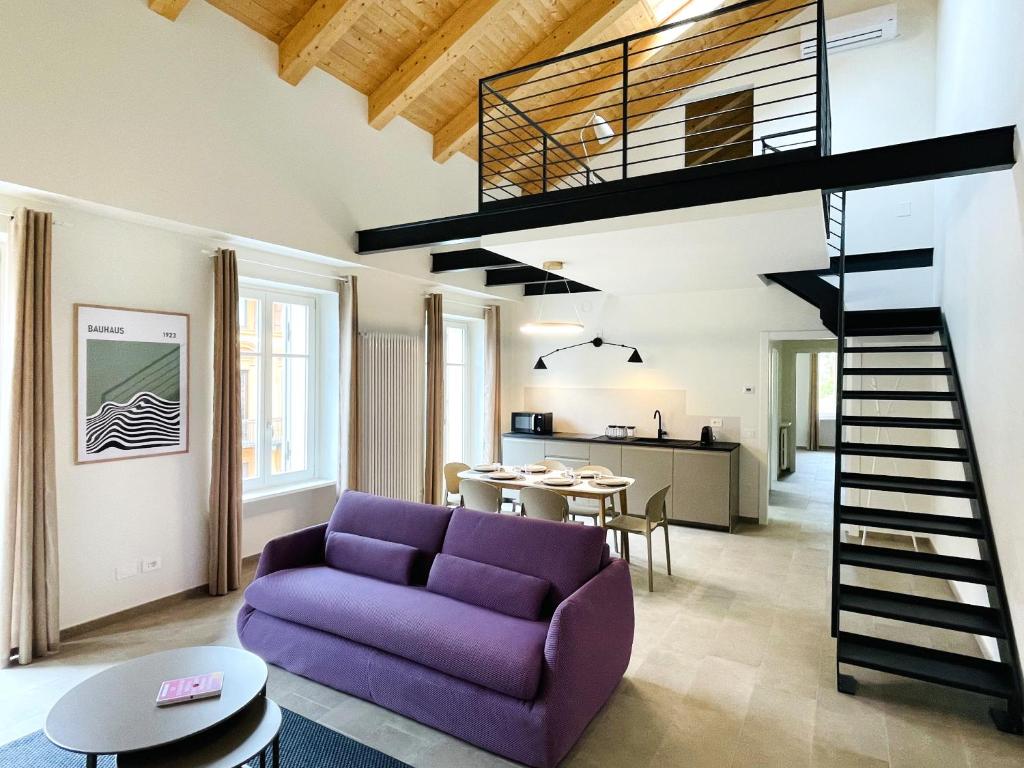 a living room with a purple couch and a spiral staircase at Casa FILA1923 in Biella