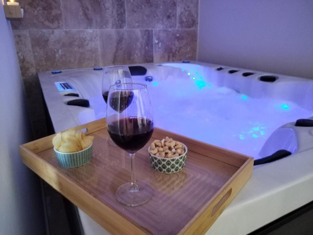a glass of wine and a bowl of food next to a hot tub at eden & Spa in Gajan