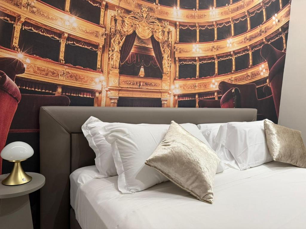 a bed with white pillows in front of a theatre at Lolli Boutique Suite Al Massimo Palermo Centro in Palermo