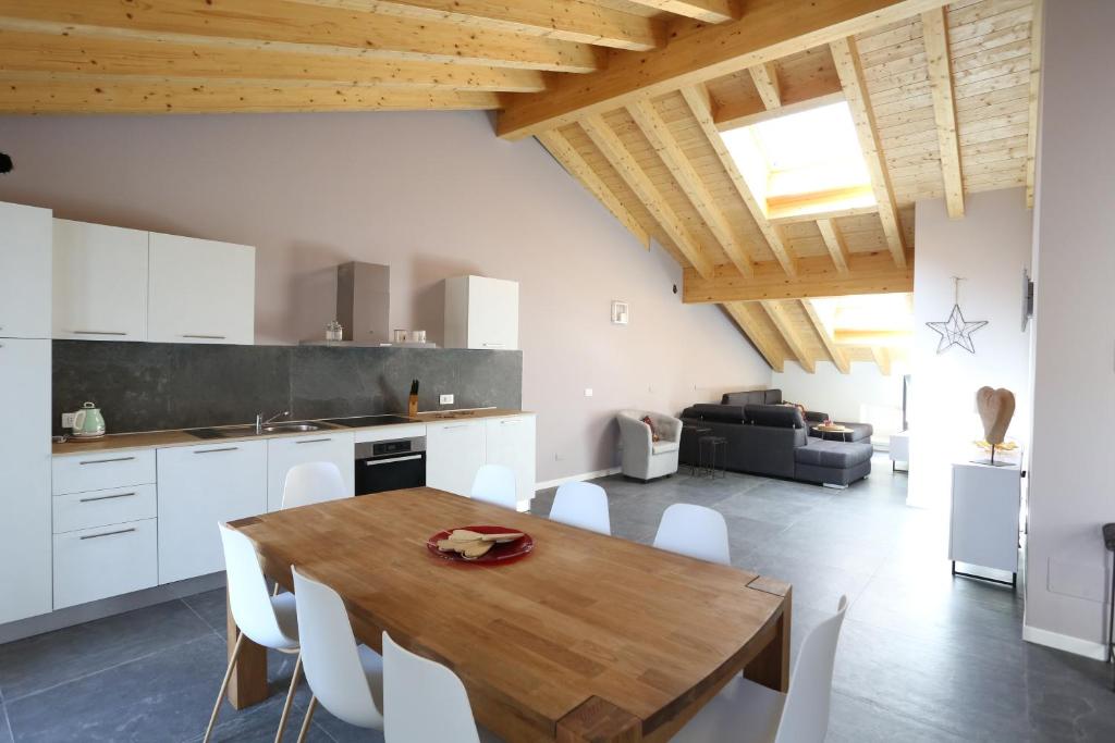 a kitchen and dining room with a wooden table and white cabinets at Casa BEA 4 in Castione della Presolana