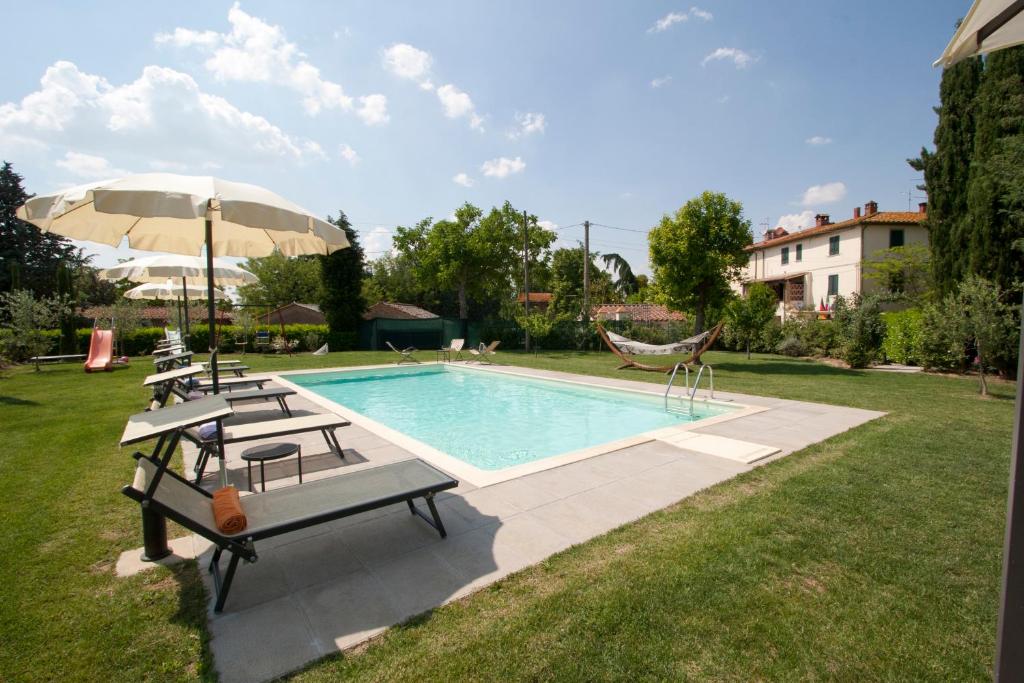 a pool with chairs and a hammock and an umbrella at Giardino Di Sara in Cortona