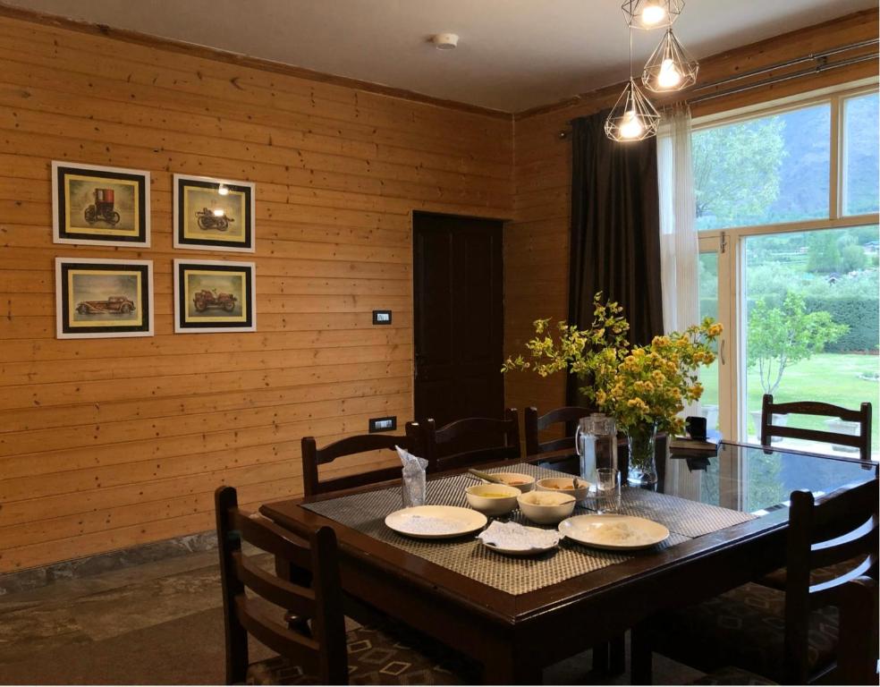 a dining room table with chairs and a wooden wall at Whistling Woods Eco Resort 