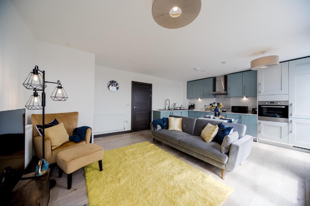 a living room with a couch and chairs and a kitchen at Step Free 2 Bed 2 bath Oasis Flat Close to David Lloyd Gym with Fully Equipped Kitchen& Parking in Dartford Mins from station and 45 mins into Central London in Dartford