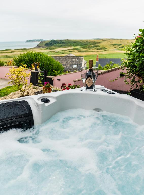 a jacuzzi tub with a view of the ocean at Priory Bay Escapes - Uminari in Tenby