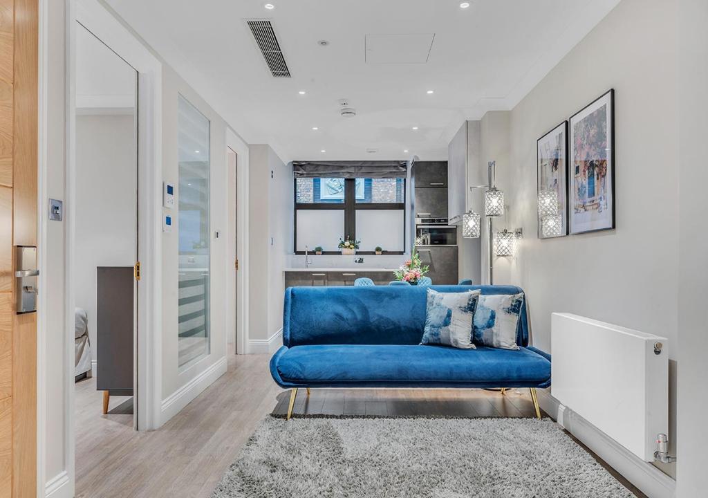 a blue couch in a living room with a window at Cleveland Residences Farringdon in London