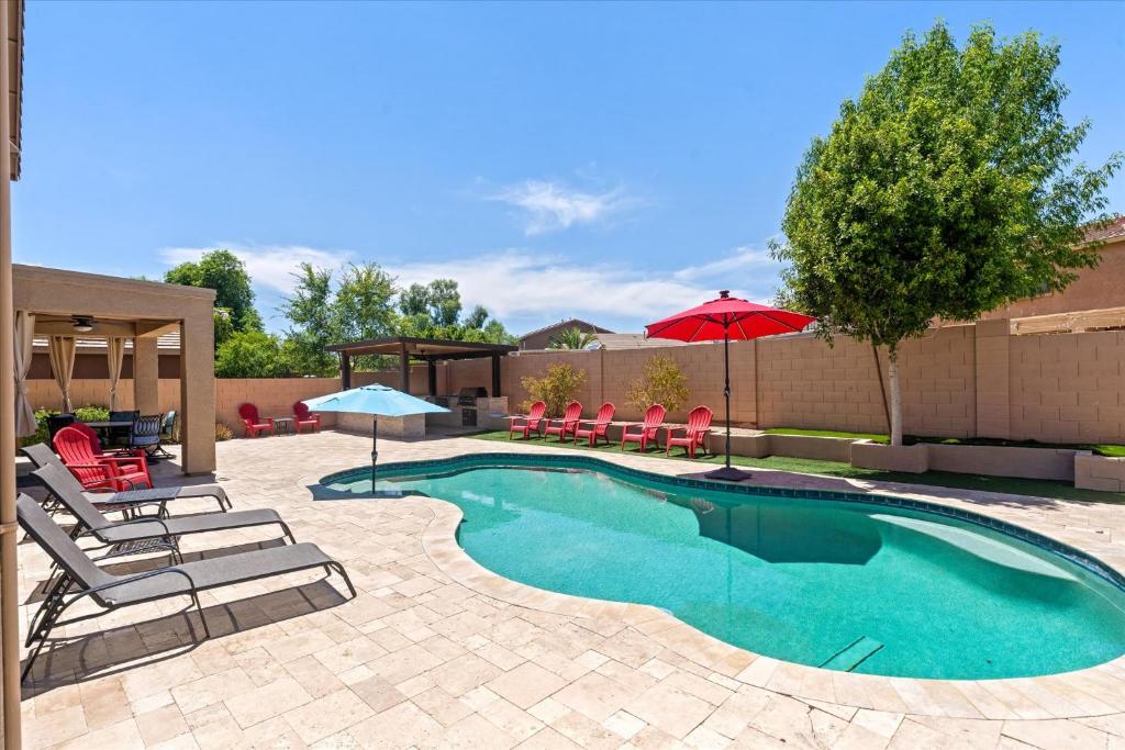 a swimming pool with lounge chairs and an umbrella at Pool Grill Games Chill - Surprise Awaits in Surprise