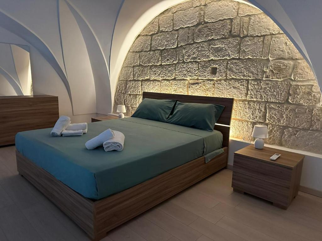a bedroom with a bed and a stone wall at Palazzo dei Pavoni in Brindisi