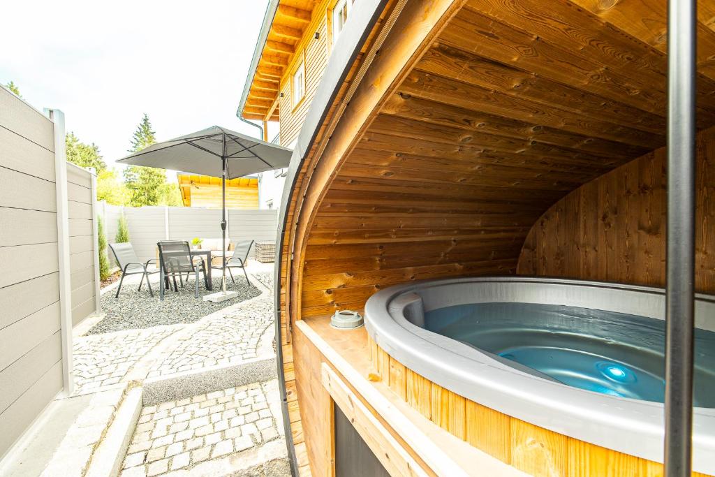 a hot tub in a wooden building with a patio at Ferienbahnhof Fichtental Stellwerk Suite in Prackenbach