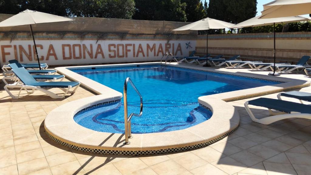 a swimming pool with chairs and umbrellas at Finca Doña Sofia Maria in San Pedro del Pinatar