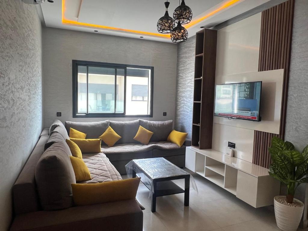 Una sala de estar con un sofá y un televisor. en Appartement familial Soleil et Mer à 150m de la Plage de Mehdia, en Plage de Mehdia