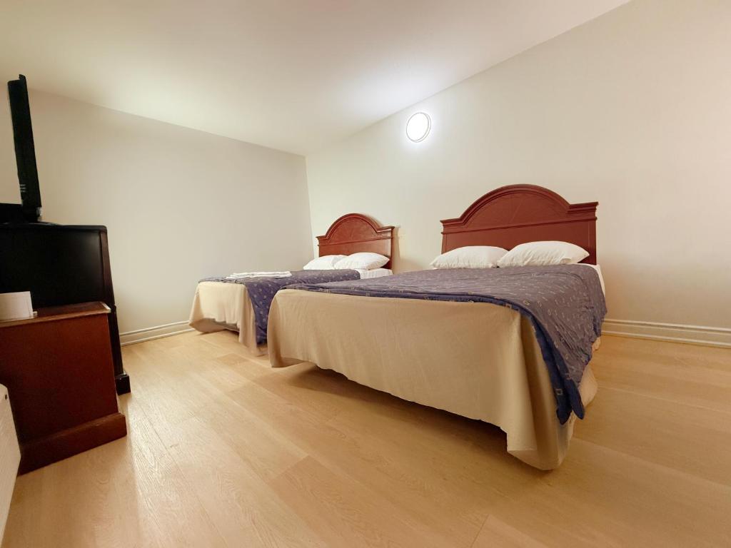 a bedroom with two beds and a flat screen tv at Idlewood Inn in Toronto