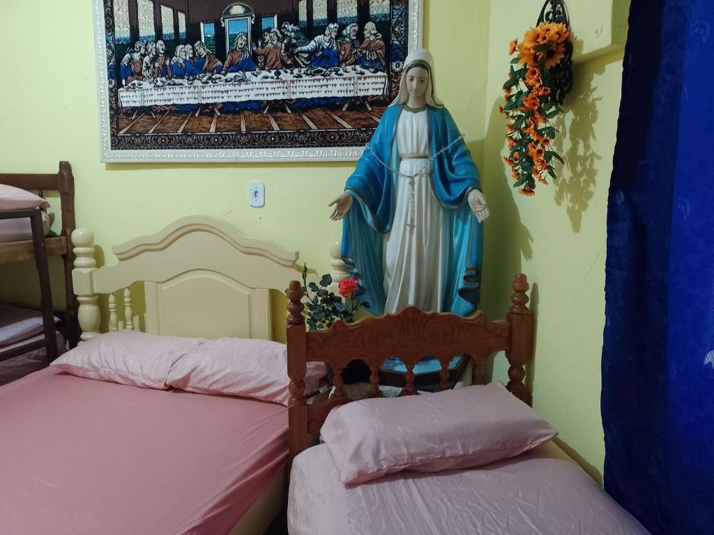 a statue of a virgin and two beds in a room at Casa da Tia Lá próximo ao Santuário Nacional preço único pela casa cabem até seis pessoas in Aparecida