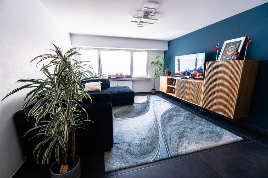 a living room with a couch and a plant at Appartement Central Luxembourg in Hesperange