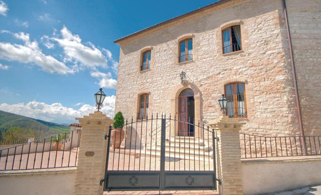 a brick building with a gate and a fence at Country House Federico I in Sassoferrato