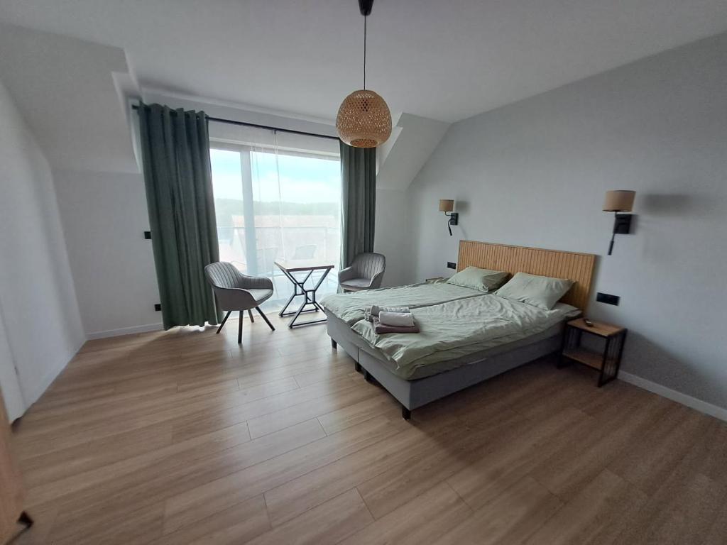 a bedroom with a bed and a table and chairs at Nad Zatoką pokoje z widokiem na jezioro in Ryn