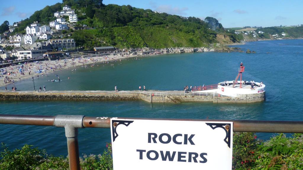 a rock towers sign with a boat in a body of water at 9 Rock Towers in Looe