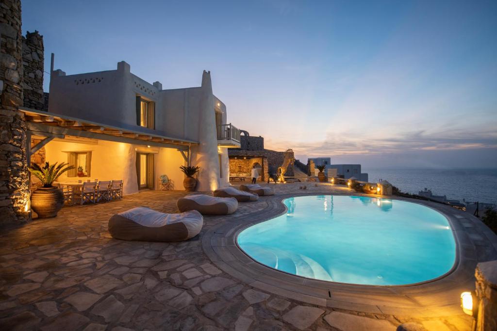 a swimming pool in front of a house with the ocean at The Aegean Residence Villa 6 Bedroom nearby the City in Kanalia Area by Hospirit in Mýkonos City