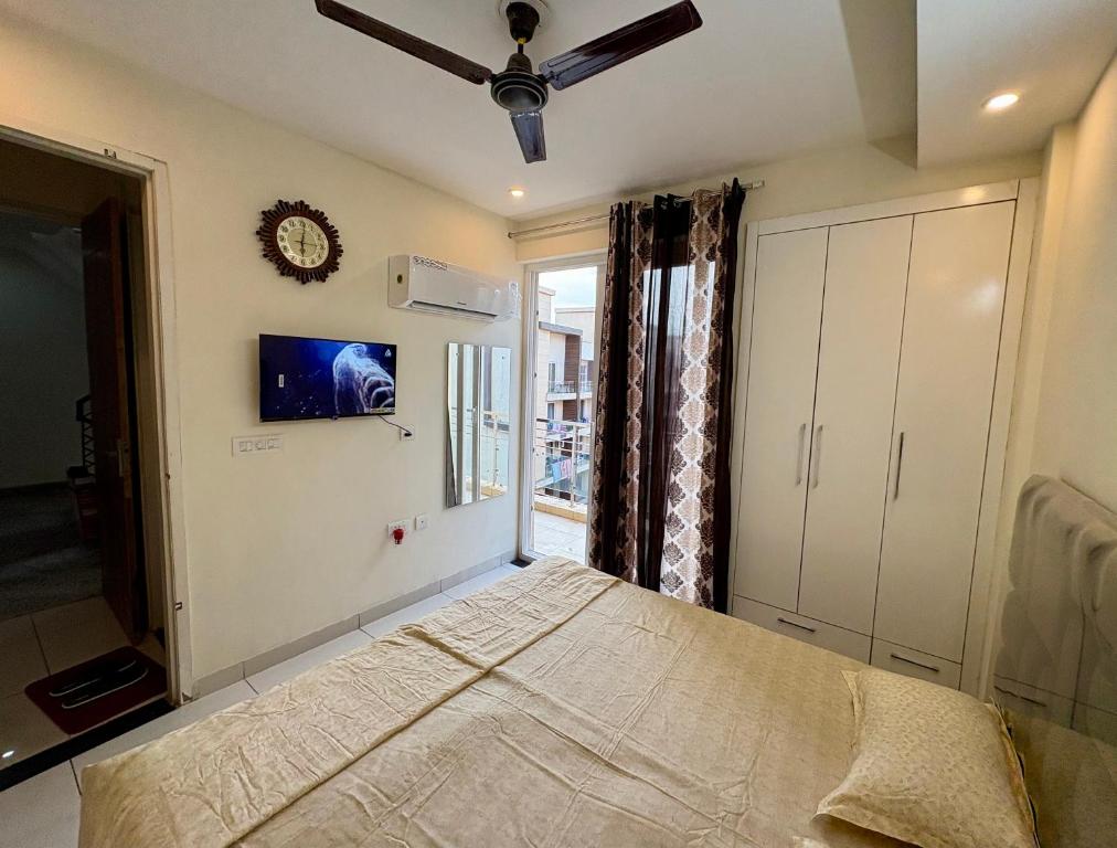 a bedroom with a bed with a ceiling fan and a window at Chandigarh Waale, Furnished Stay in Zirakpur in Zirakpur