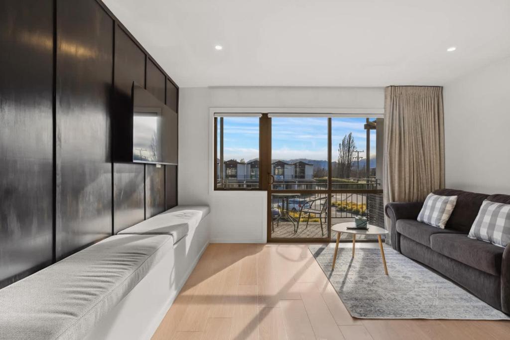 a living room with a couch and a large window at Wanaka Ridge in Wanaka