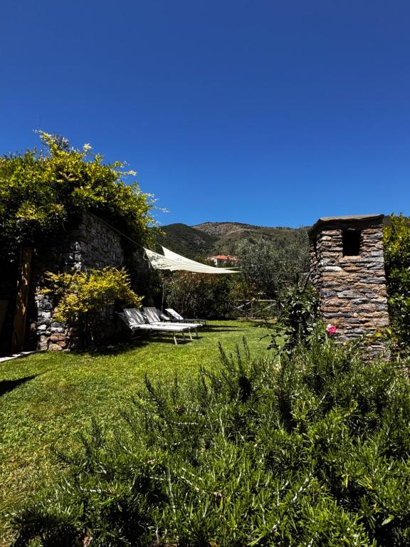 a yard with a stone building and a bench at La Casa negli Ulivi - con vista Mare in Arnasco