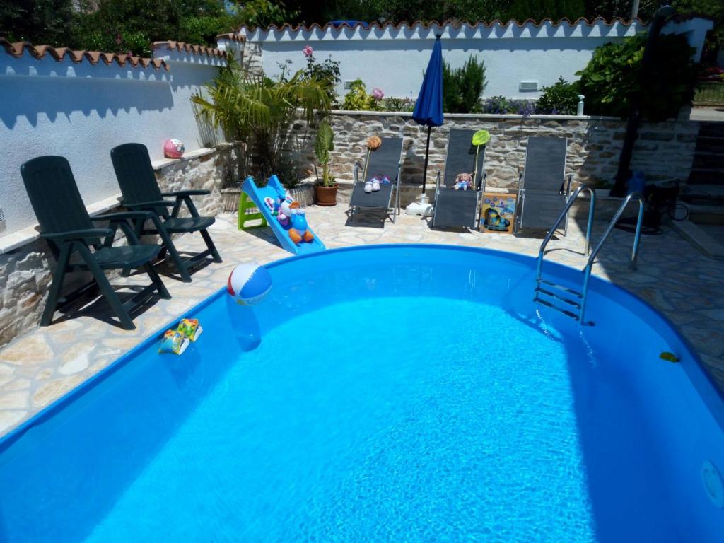 a large blue swimming pool with two chairs in a yard at Apartments Val in Umag