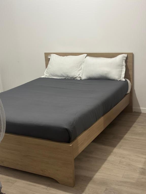 a bed with a wooden frame with two pillows on it at Studio Bethel cosy à Villejuif centre Paris in Villejuif